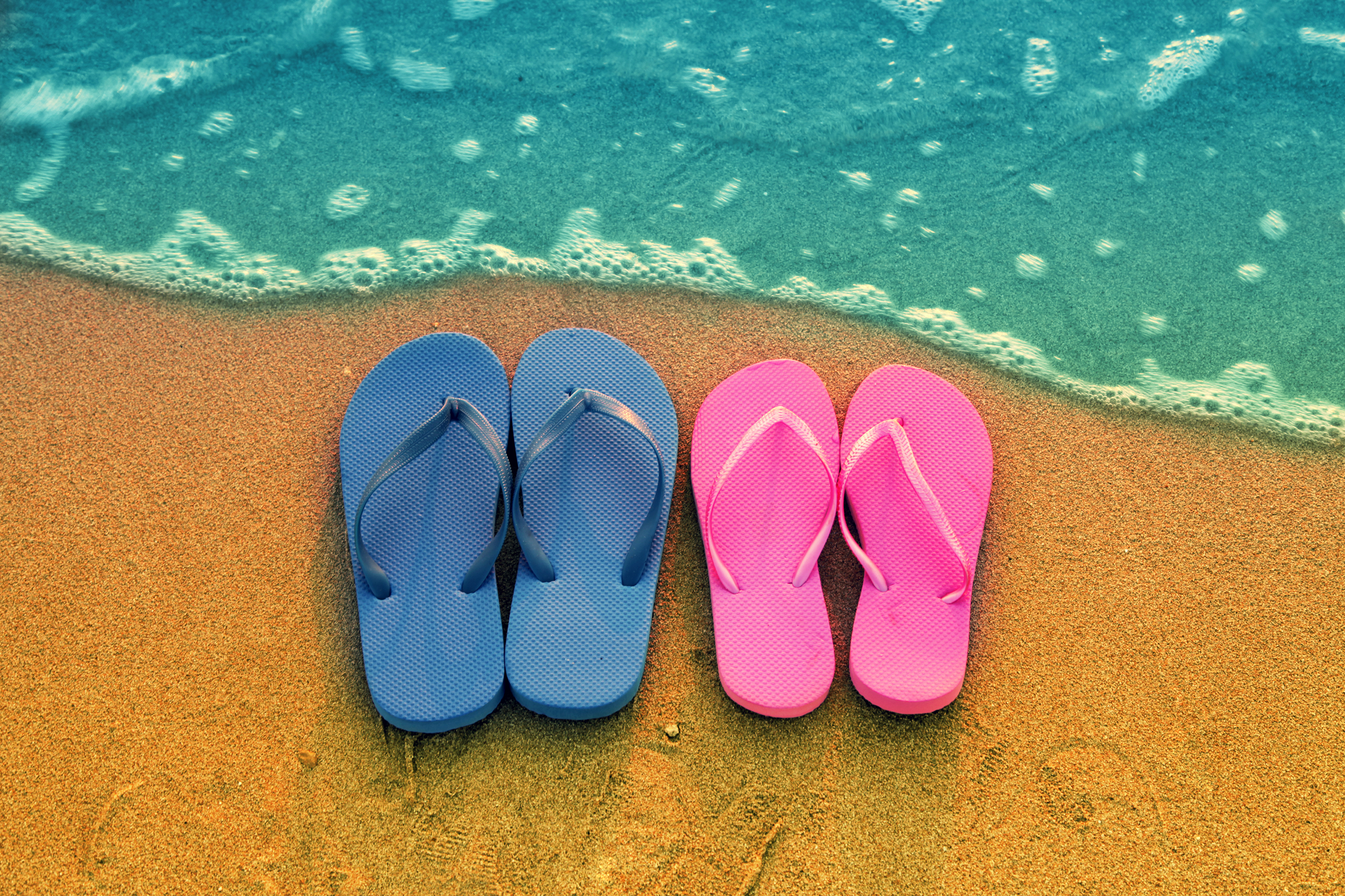 Romantic beach scene. Female and male flip flpp sandals on the beach